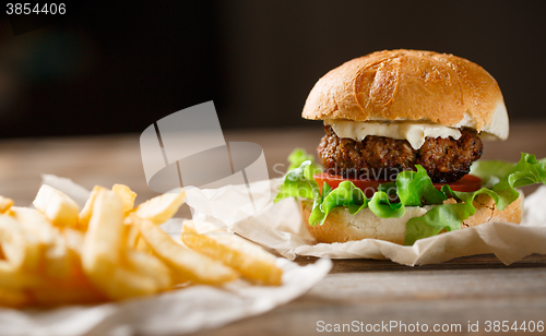 Image of homemade burger and french fries on a wooden plate