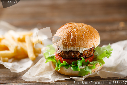 Image of homemade burger and french fries on a wooden plate