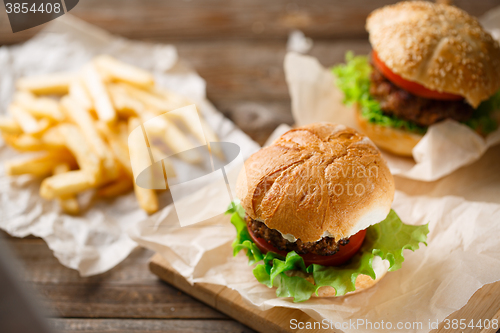 Image of Homemade tasty burger and french fries on wooden table