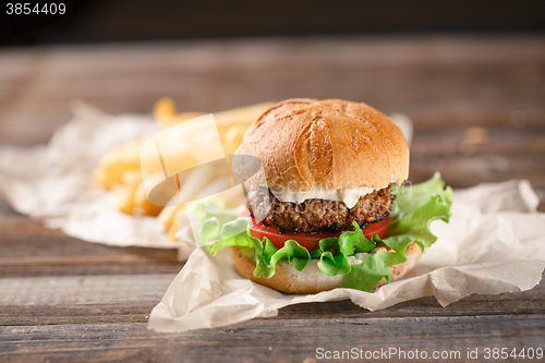 Image of Homemade burger with french fries on wooden table