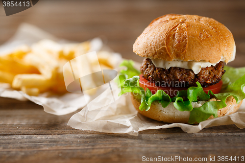 Image of homemade burger and french fries on a wooden plate