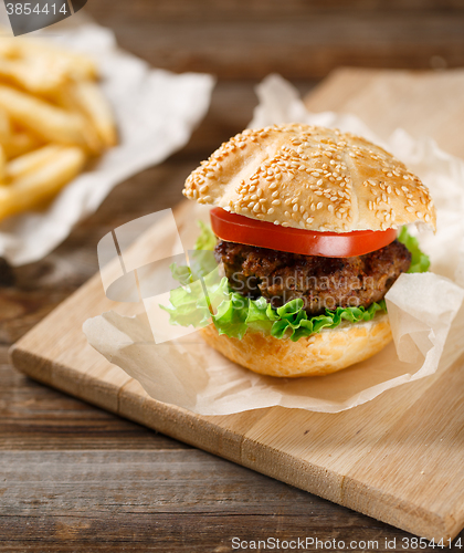 Image of Homemade hamburgers and french fries on wooden table