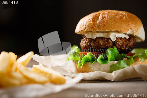 Image of homemade burger and french fries on a wooden plate