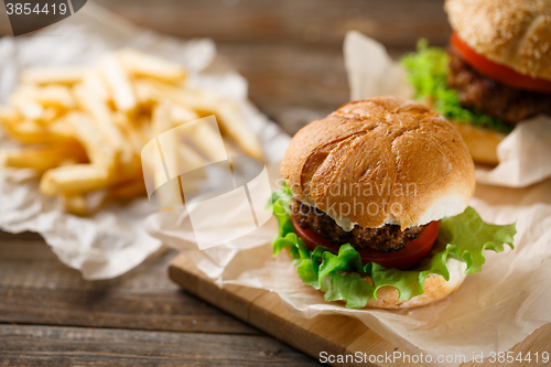 Image of Homemade hamburgers and french fries on wooden table