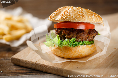 Image of Homemade hamburgers and french fries on wooden table