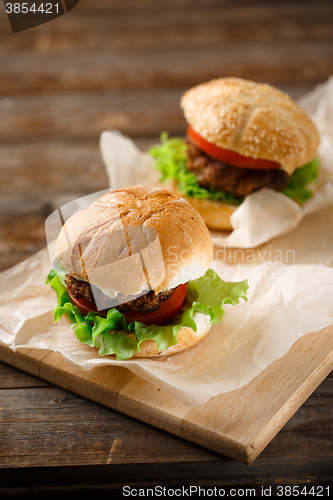 Image of Homemade hamburgers and french fries on wooden table