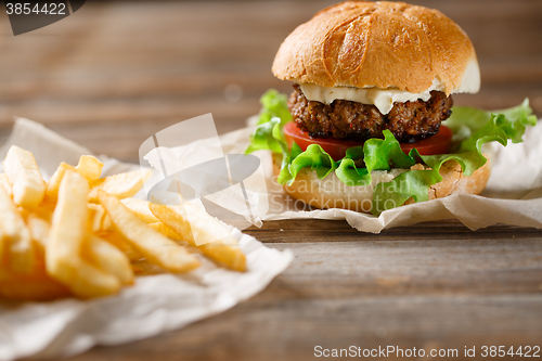 Image of homemade burger and french fries on a wooden plate