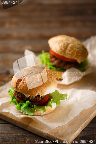 Image of Homemade hamburgers and french fries on wooden table