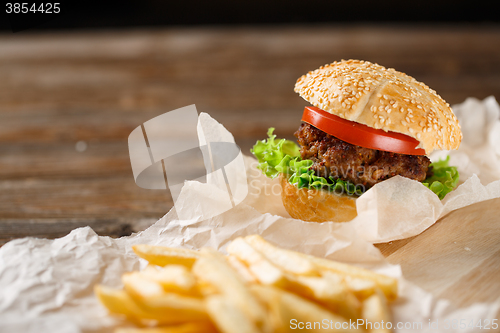 Image of Homemade hamburgers and french fries on wooden table