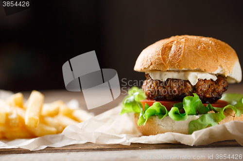 Image of homemade burger and french fries on a wooden plate