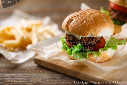 Image of Homemade tasty burger and french fries on wooden table