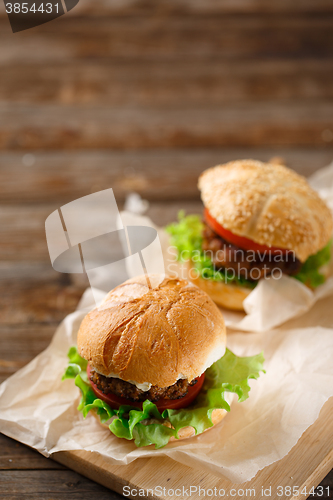 Image of Homemade hamburgers and french fries on wooden table