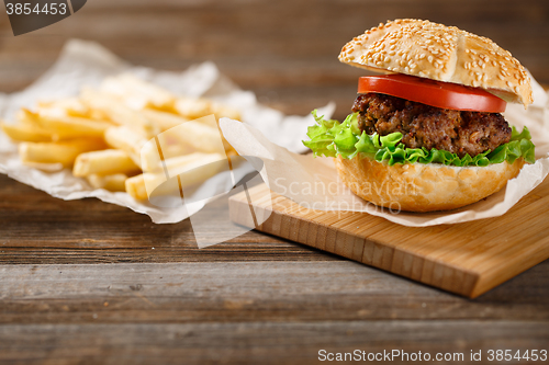 Image of Homemade hamburgers and french fries on wooden table