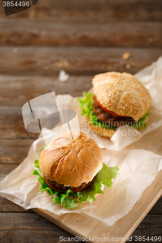 Image of Homemade hamburgers and french fries on wooden table