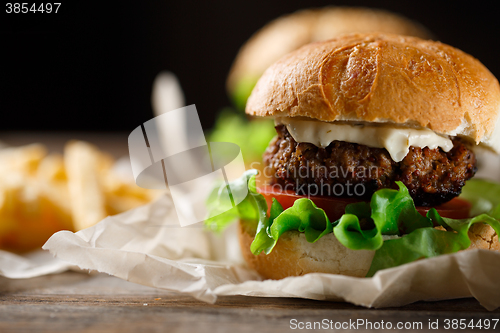 Image of Homemade tasty burger and french fries on wooden table