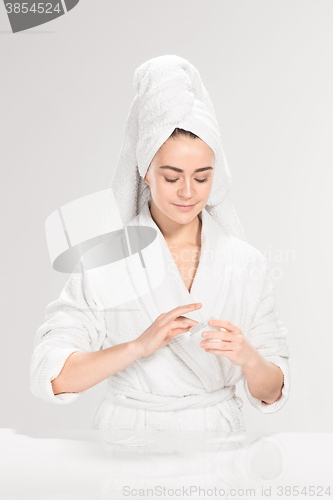 Image of Woman cleaning face in bathroom