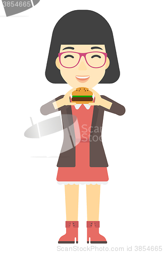 Image of Woman eating hamburger. 