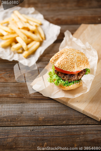 Image of Homemade hamburgers and french fries on wooden table