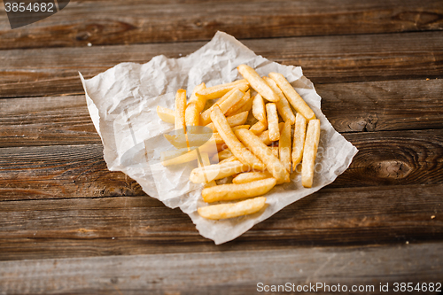 Image of French fries on wooden table.