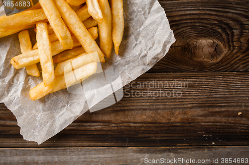 Image of French fries on wooden table.