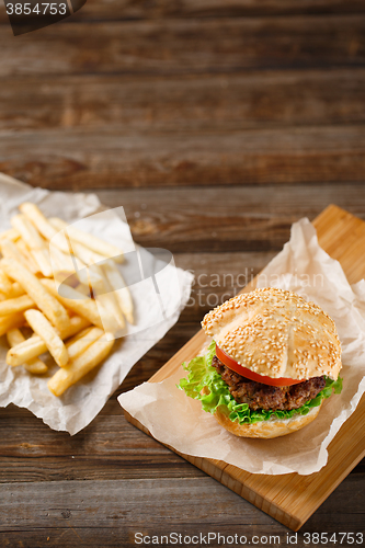 Image of Homemade hamburgers and french fries on wooden table