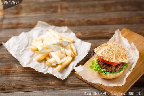 Image of Homemade hamburgers and french fries on wooden table