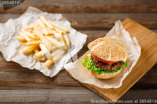 Image of Homemade hamburgers and french fries on wooden table