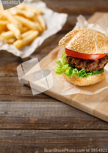 Image of Homemade hamburgers and french fries on wooden table