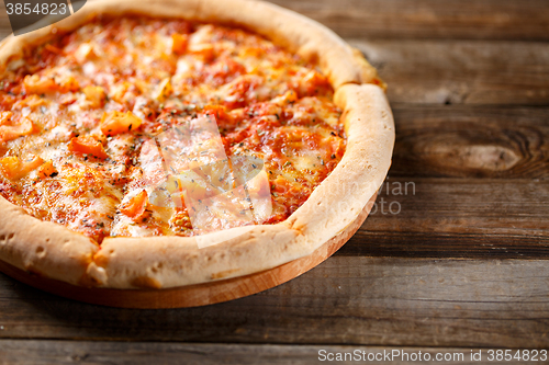 Image of Tasty pizza on old wooden table.