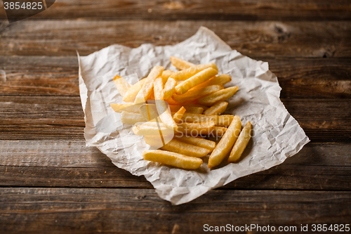 Image of French fries on wooden table.