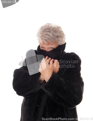 Image of Senior woman hiding in her fur coat.
