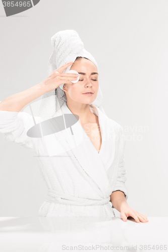 Image of Woman cleaning face in bathroom