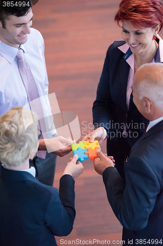 Image of top view of business people group assembling jigsaw puzzle