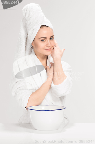 Image of Woman cleaning face in bathroom