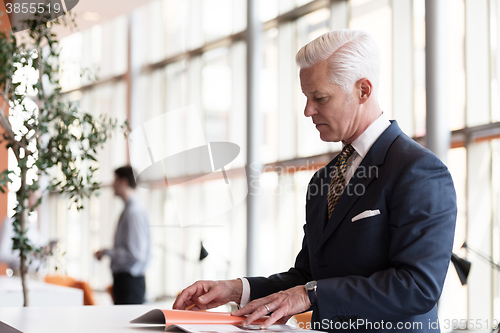 Image of senior business man reading magazine