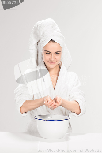 Image of Woman cleaning face in bathroom