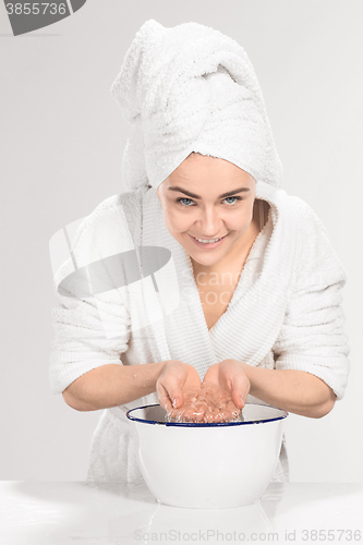 Image of Woman cleaning face in bathroom