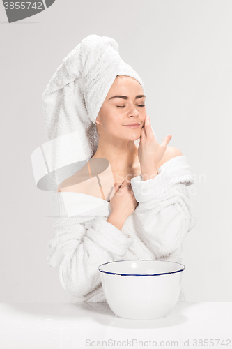 Image of Woman cleaning face in bathroom