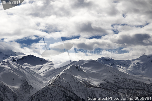 Image of View on snowy mountains and cloudy sky in evening