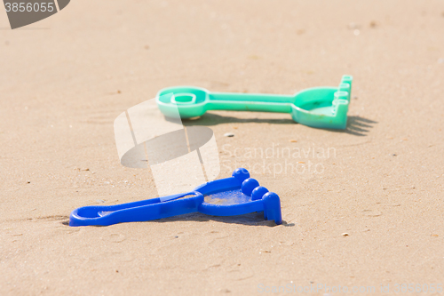 Image of  Childrens toy rake lying on the sand