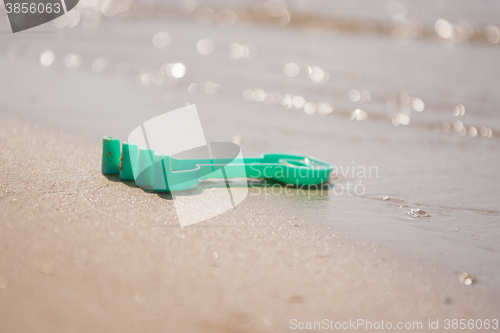 Image of Childrens toy rake, forgotten on the shore near the water