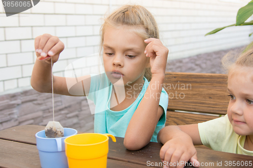 Image of A girl of six years of brewing a cup of tea from a bag