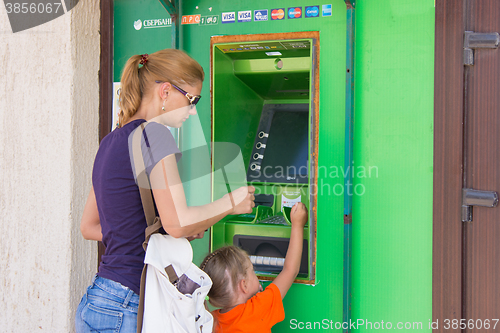 Image of Anapa, Russia - September 20, 2015: A young girl with the child to withdraw money from the ATM Sberbank