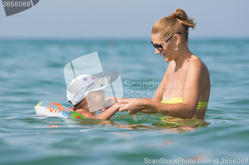 Image of Joyful mother and daughter swimming in the sea