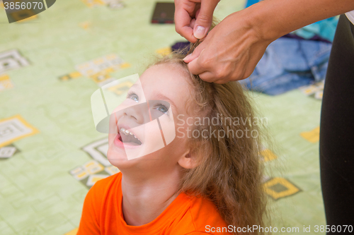 Image of A girl of four years old sitting and laughing happily, when she made her hair