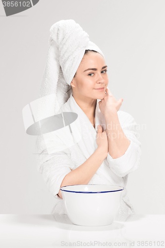 Image of Woman cleaning face in bathroom