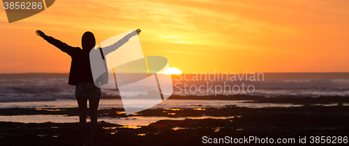 Image of Free woman enjoying freedom on beach at sunset.