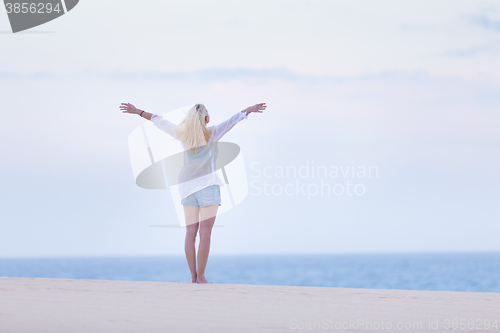 Image of Free woman enjoying freedom on beach in morning.