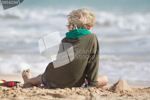 Image of Boy playing with toys on beach.