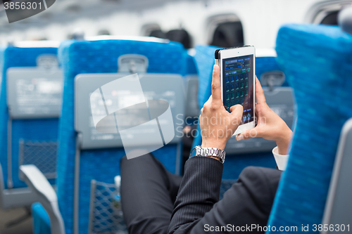 Image of Businessman using tablet phone on airplane.